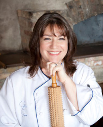 picture of a female chef smiling while holding a rolling pin